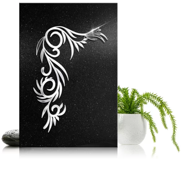Biały ornament nagrobny w kształcie roślinnego wzoru na czarnym granitowym tle obok białej doniczki z zielonymi roślinami.